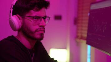 dados analista trabalhando em computador configuração com dual monitores dentro uma colorida ambiente luz às casa estúdio durante tarde horas video