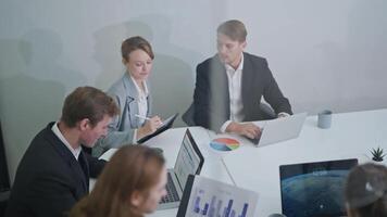 Team collaboration at a corporate meeting with data analysis and presentations in a modern office video
