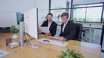 Two professionals discuss project details at a modern office during a meeting about strategic plans and data analysis video