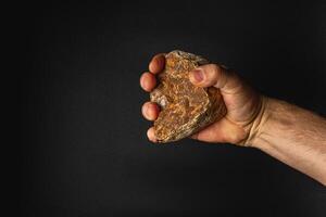 Hand holding a rock against a dark background photo
