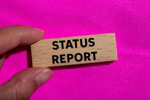 Status report message written on wooden block on pink background. Conceptual status report symbol. Copy space. photo