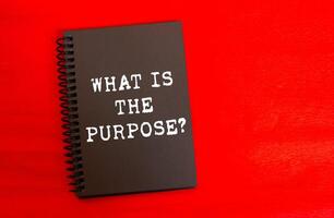 What is the purpose message written on black notebook page on red background. Conceptual what is the purpose symbol. Copy space. photo