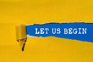 Let us begin message written on ripped torn yellow paper on blue background. Conceptual let us begin symbol. Copy space. photo