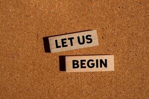 Let us begin message written on wooden blocks on brown background. Conceptual let us begin symbol. Copy space. photo
