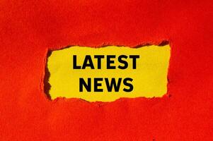 Latest news message written on ripped torn red paper on yellow background. Conceptual latest news symbol. Copy space. photo