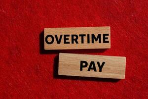 Overtime pay message written on wooden blocks on red background. Conceptual overtime pay symbol. Copy space. photo