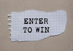 Enter to win message written on ripped torn paper piece on paper background. Conceptual enter to win symbol. Copy space. photo