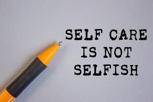 Self care is not selfish message written on gray background with a pen. Conceptual self care is not selfish symbol. Copy space. photo