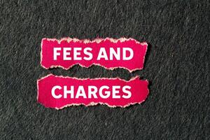 Fees and charges message written on ripped torn pink paper pieces on gray background. Conceptual fees and charges symbol. Copy space. photo