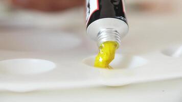 Yellow paint squeezes from a tube onto a mixing palette video