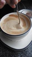 Stirring rich coffee with creamy froth in a cozy cafe setting video