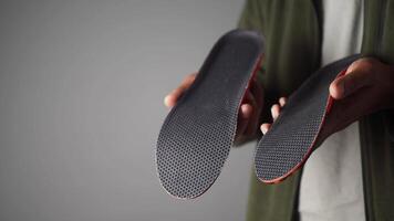 Shoe insoles displayed by a person in a neutral background video