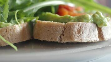 Fresh avocado toast topped with greens in a cozy cafe setting video