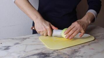 The girl chops and finely chops white onions on a light cutting board. Cooking video