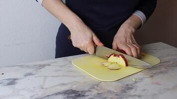 The cook chops a red apple into pieces on a cutting board. Preparation of salad video