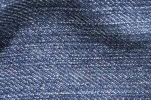 Close-up texture of blue denim fabric showing detailed weave pattern in high resolution. photo
