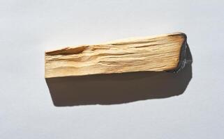 Close up of a textured piece of wood with natural grain patterns and shadows on a light background. photo