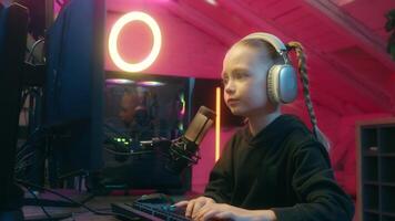 Little girl gamer streamer worried difficult troubled streaming typing keyboard daughter child kid playing computer play virtual game online home neon pointing monitor screen talking microphone video