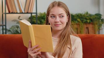 Young woman reading interesting book turning pages smiling enjoying literature taking rest on sofa video