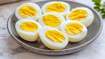 A plate of halved boiled eggs showcasing bright yellow yolks and smooth white egg whites, garnished with parsley on a light background. photo