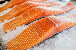 Fresh salmon fillets arranged on ice, showcasing vibrant orange color and distinctive marbling, ideal for culinary presentations. photo