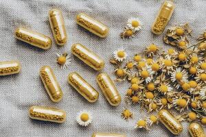A collection of yellow capsules scattered on a textured surface, accompanied by dried chamomile flowers, creating a calming and herbal aesthetic. photo