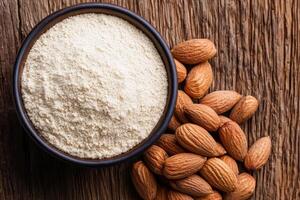 A bowl of almond flour alongside whole almonds on a rustic wooden surface, showcasing natural ingredients for baking and cooking. photo