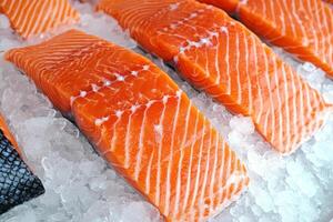 Fresh salmon fillets on ice, showcasing vibrant orange color and distinct marbling, ready for culinary preparation or display. photo
