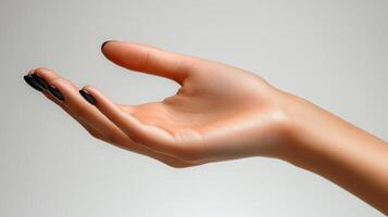 A hand with a black manicured nail is reaching out photo