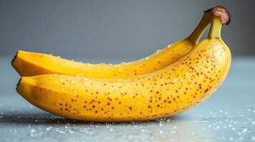 Freshly picked bananas with droplets of water on a gray surface highlighting their vibrant yellow color photo