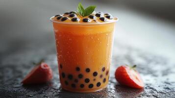 Refreshing bubble tea served in a clear cup with strawberries on a wet surface photo