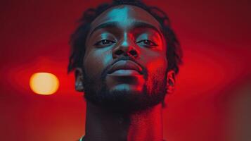 Portrait of a young man with intricate hairstyle illuminated by red and orange lighting in an artistic setting photo