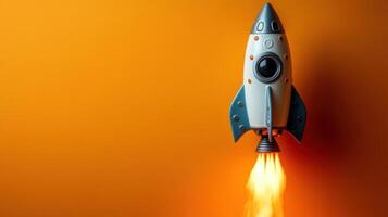 Toy rocket launching against a vibrant orange background with flames propelling from the engine photo