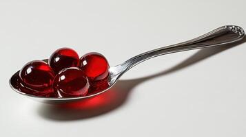 Red gelatin spheres on a silver spoon, showcasing vibrant colors and glossy surface photo