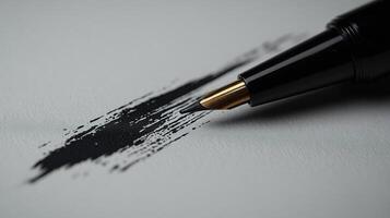 Black ink flows from a pen onto a sheet of paper, creating an artistic brush stroke in a minimalist workspace photo
