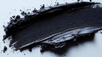 Thick black paint smeared across a smooth surface during an art project in a creative studio photo
