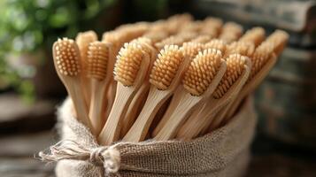 Eco-friendly bamboo toothbrushes arranged in a rustic burlap sack on a wooden surface in a natural setting photo