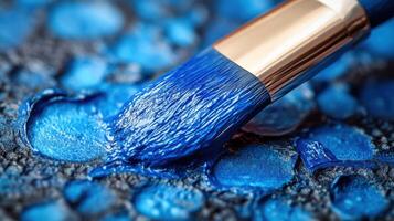 Close-up of a brush applying vibrant blue paint on textured canvas in an artist's studio during daytime photo