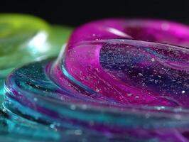Abstract image featuring close-up view of swirling glossy textures in vibrant pink, blue, and green hues, interspersed with sparkling gold flecks. Focus on fluid and dynamic shapes photo