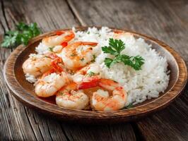 Shrimp garnished with parsley sit atop fluffy white rice on a rustic wooden plate, creating an appetizing presentation enhanced by a textured wood table backdrop photo