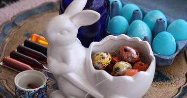 Easter eggs and quail eggs in a bunny shaped bowl with colorful dye for decorating eggs during spring celebrations photo