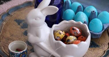 Colorful Easter eggs and quail eggs arranged in a festive Easter Bunny shaped bowl on a decorative plate photo