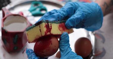 Creative process of coloring Easter eggs with red dye using a sponge technique in a cozy indoor setting during the festive spring season photo