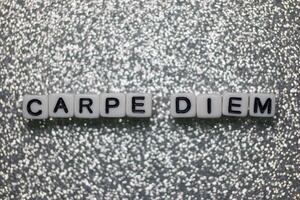 Inspirational message of carpe diem displayed on white letter tiles against a glittery silver background photo