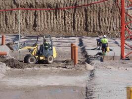 Construction site activity featuring machinery and workers at a development project in sunny conditions photo