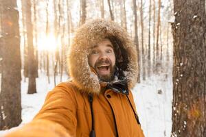 Excited man enjoying winter forest walk and taking selfie. Joy, freedom and connection with nature during the snowy season. photo