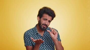 Indian man showing a little bit gesture with sceptic smile showing minimum sign measuring small size video
