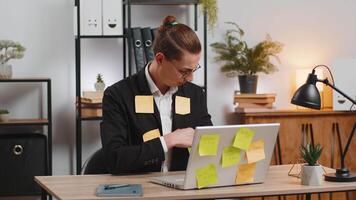 Tired exhausted businessman with laptop sticky notes with many tasks sitting at home office desk video
