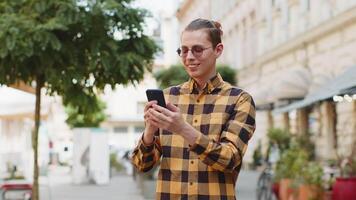 Happy smiling young man tourist using smartphone browsing internet social media web app chatting video