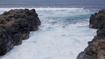Waves crashing between rocky cliffs at a coastal location video